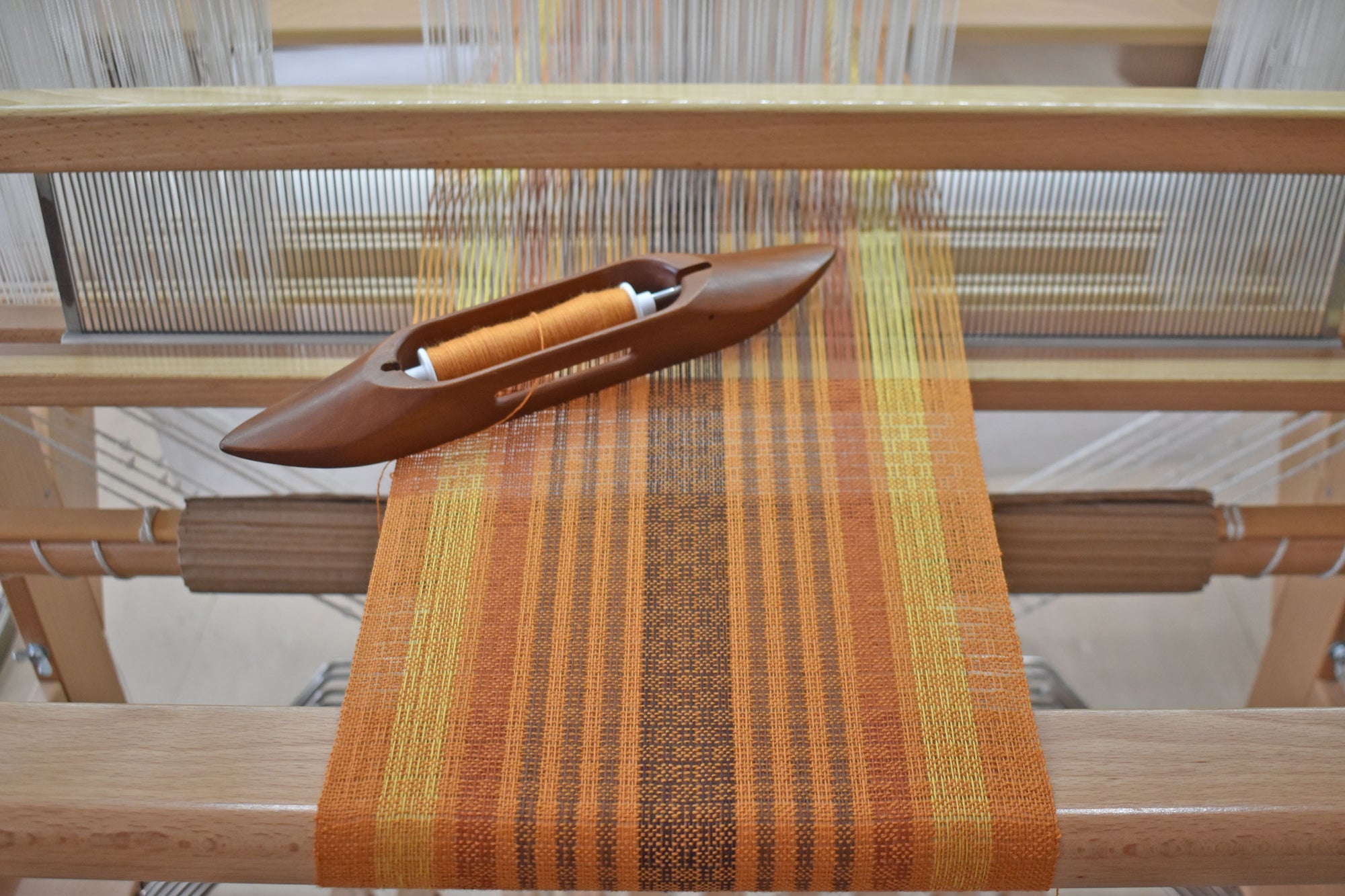 This handwoven wool scarf on the handloom. The shuttle used to weave is also shown.