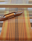 This handwoven wool scarf on the handloom. The shuttle used to weave is also shown.