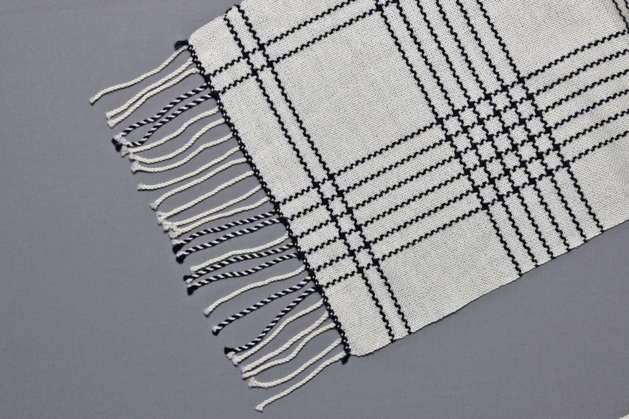 Close-up the hand twisted fringes on the white handwoven merino wool scarf