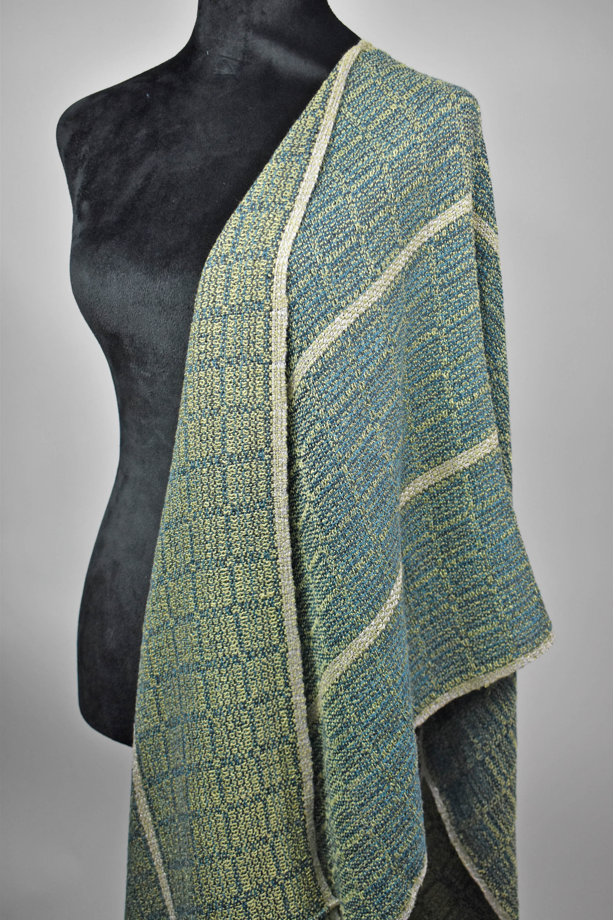 Blue and green shawl draped off the shoulder of the mannequin. Shows the two different sides of the fabric.