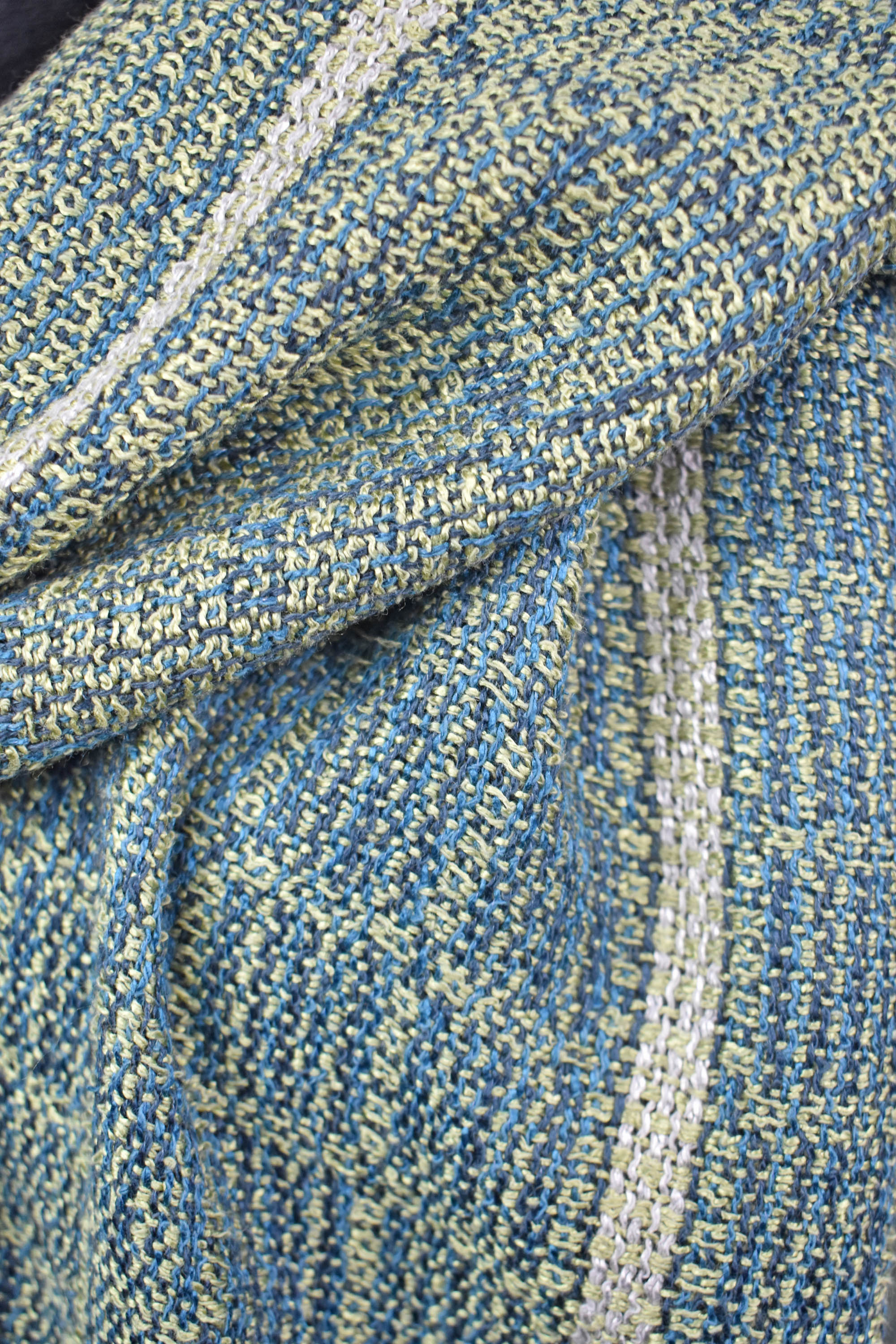 Close up view of the handwoven blue and green scarf. One side of the scarf is blue and the other is green.