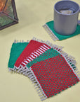 Handwoven Christmas mug rugs on a yellow table with a lantern and a cup of tea.